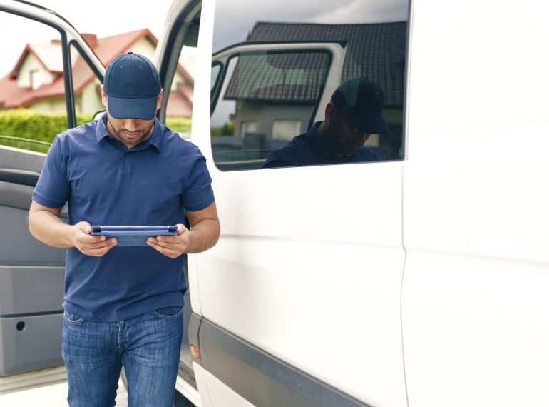 Driver with digital tablet gets out of the car