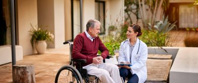 Shot of a young doctor and her elderly patient talking while sitting outside.